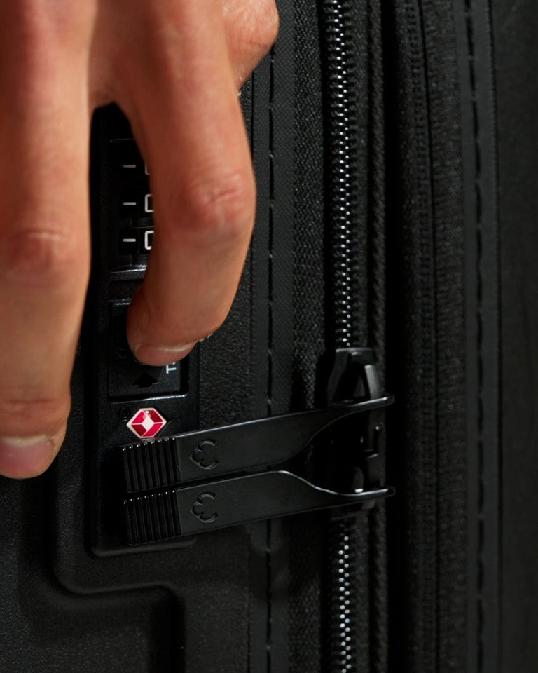 a hand pressing a button on a black suitcase