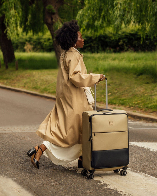 a woman in a trench coat pulling a suitcase