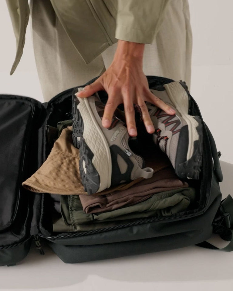 a person holding shoes in a suitcase