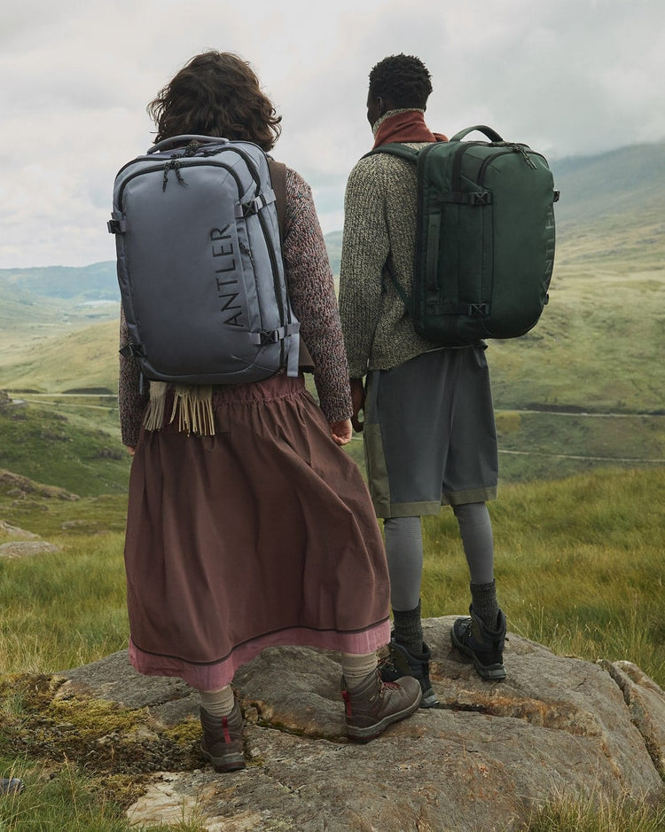 a man and woman with backpacks standing on a rock