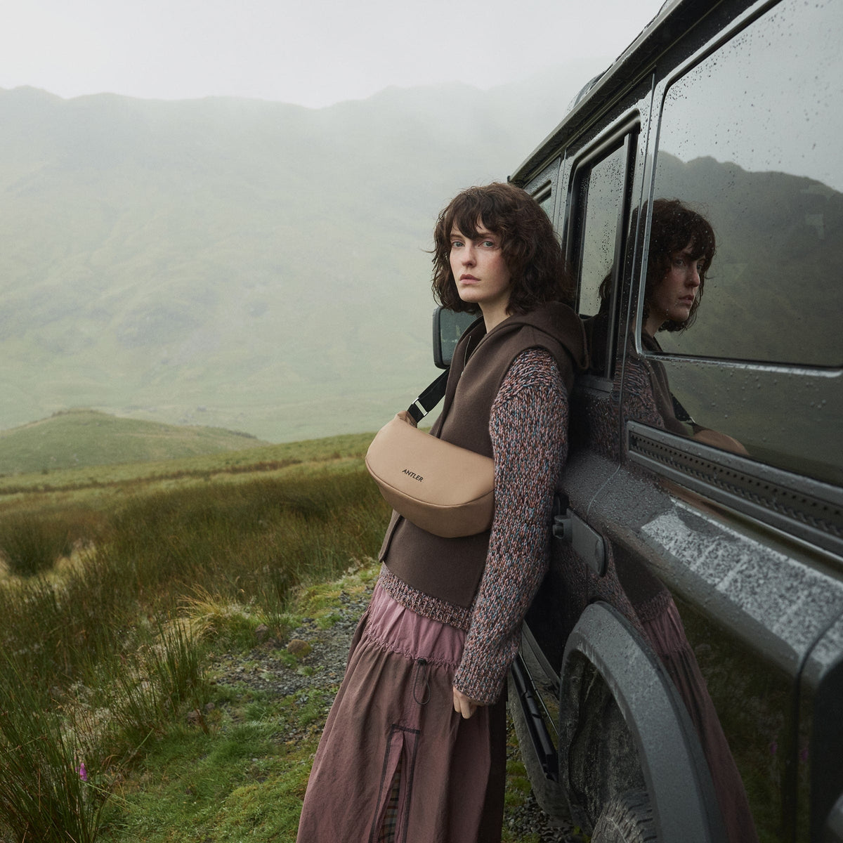 a woman leaning against a car