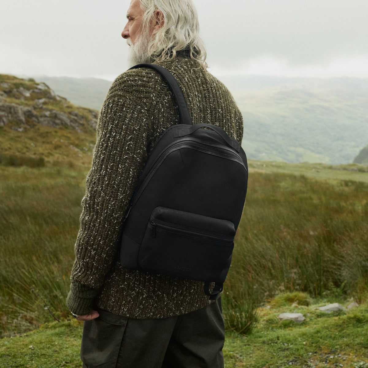 a man with a backpack standing in a grassy area