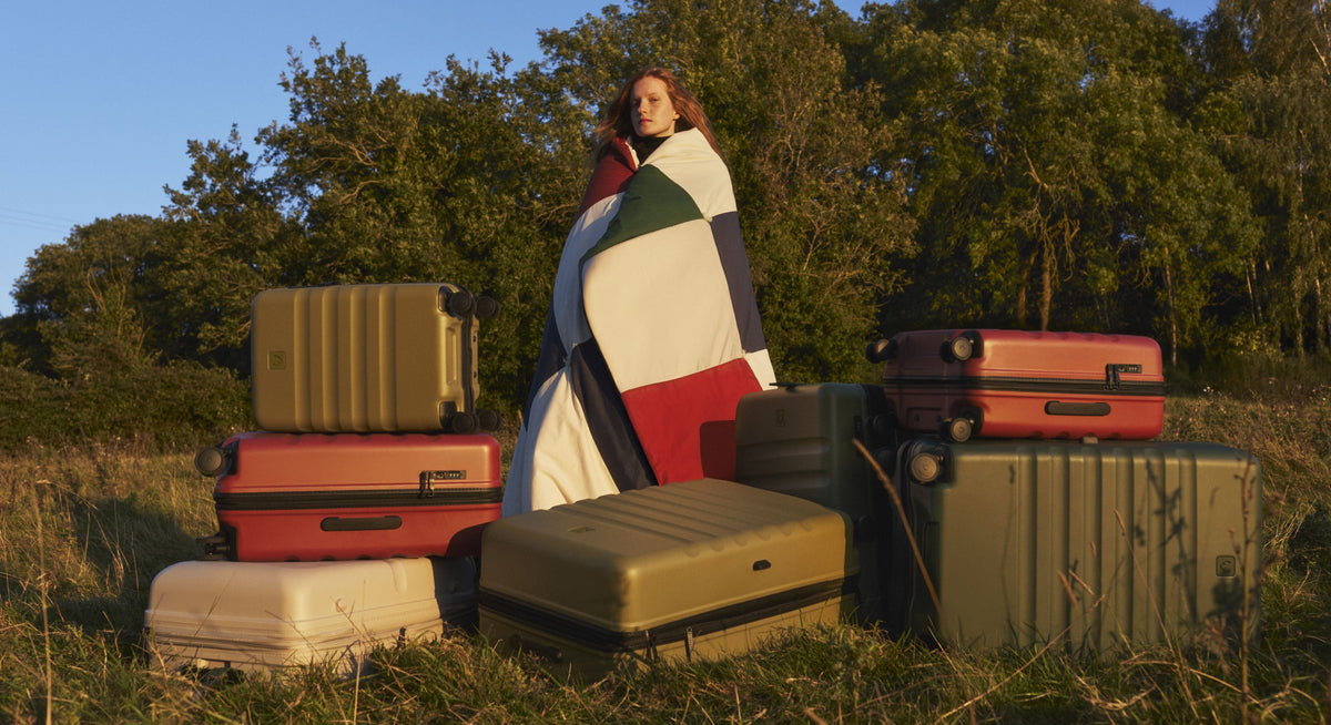 a woman wrapped in a blanket standing in front of a pile of luggage