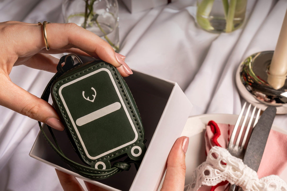 a person holding a small green keychain in a box