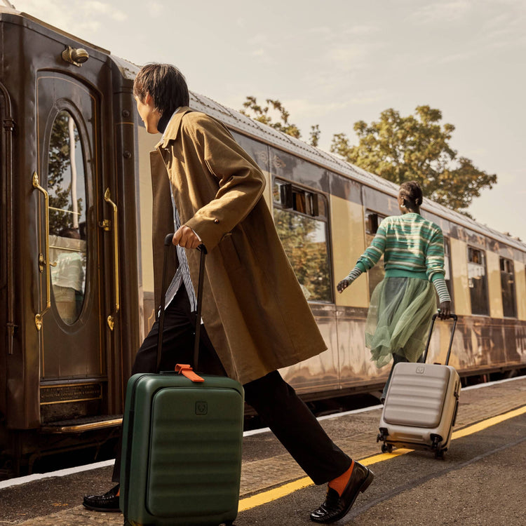 a man and woman with luggage walking by a train