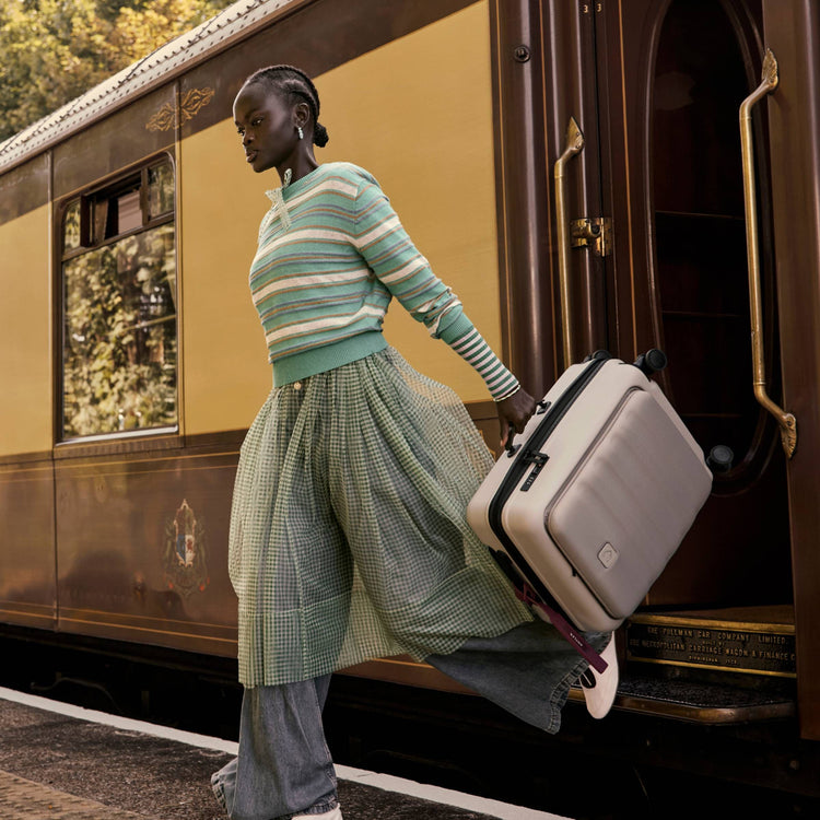 a woman walking on a train with a suitcase