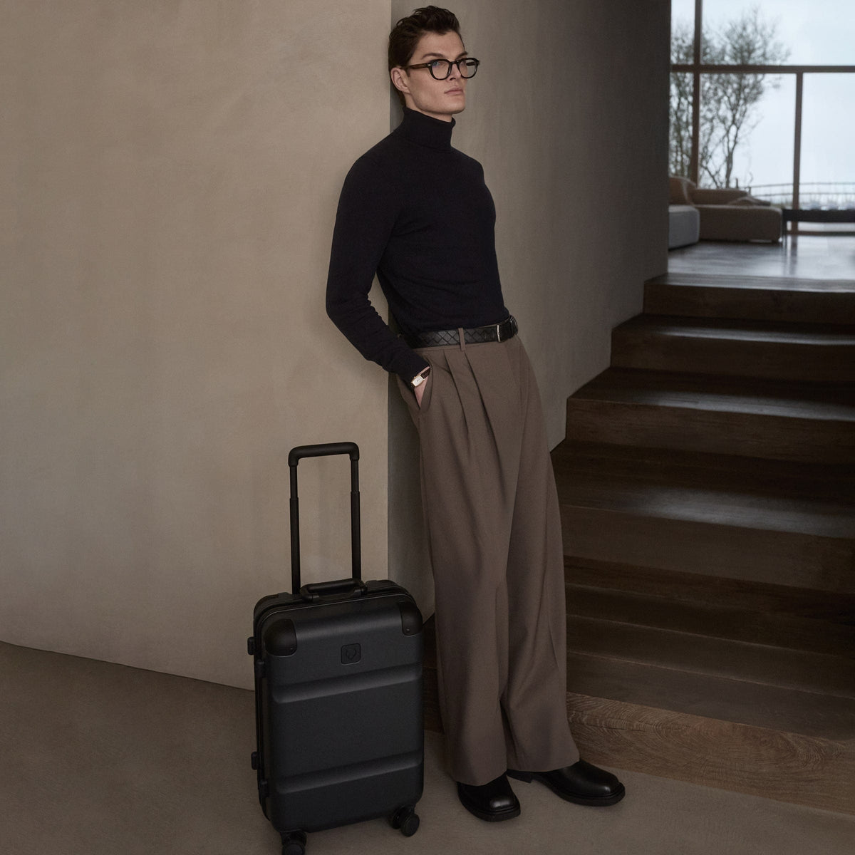 a man leaning against a wall with a suitcase