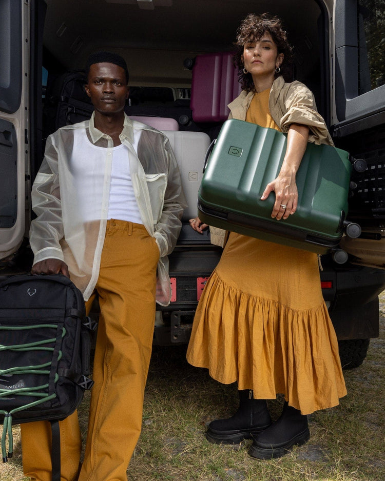 a man and woman holding luggage in the back of a van