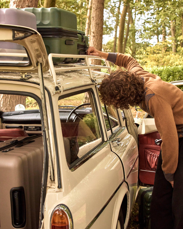 a man looking at luggage on top of a car