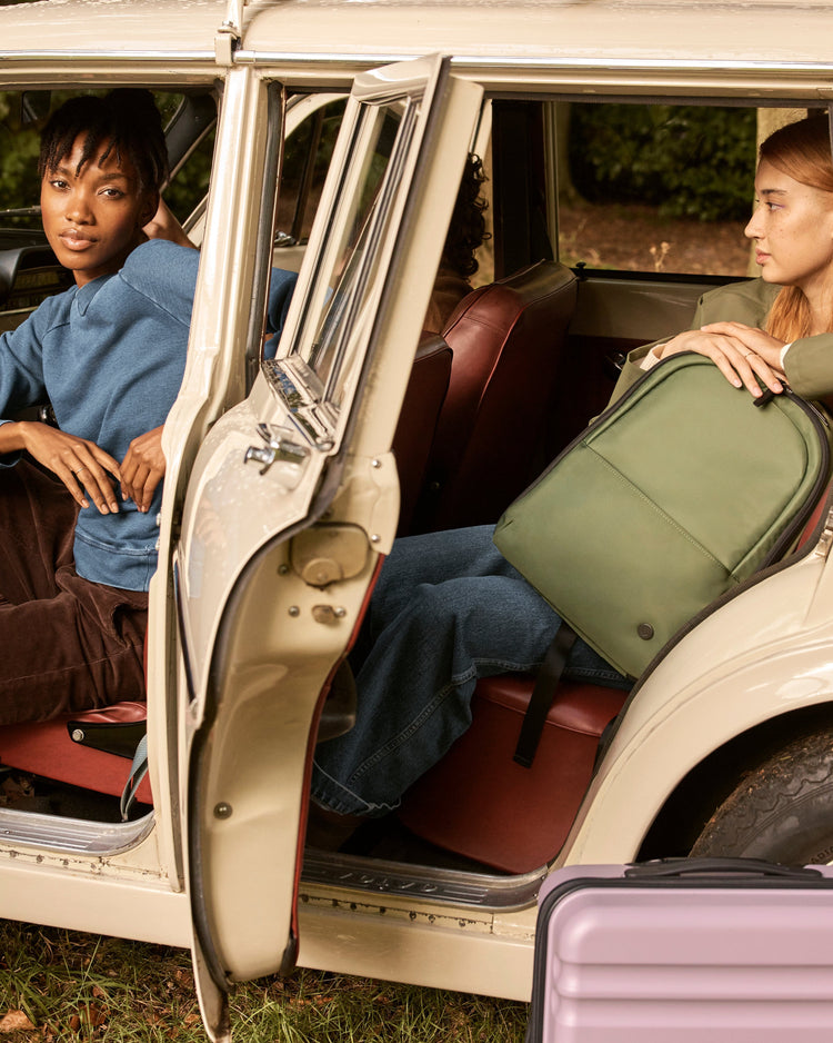 a couple of women sitting in a car with luggage