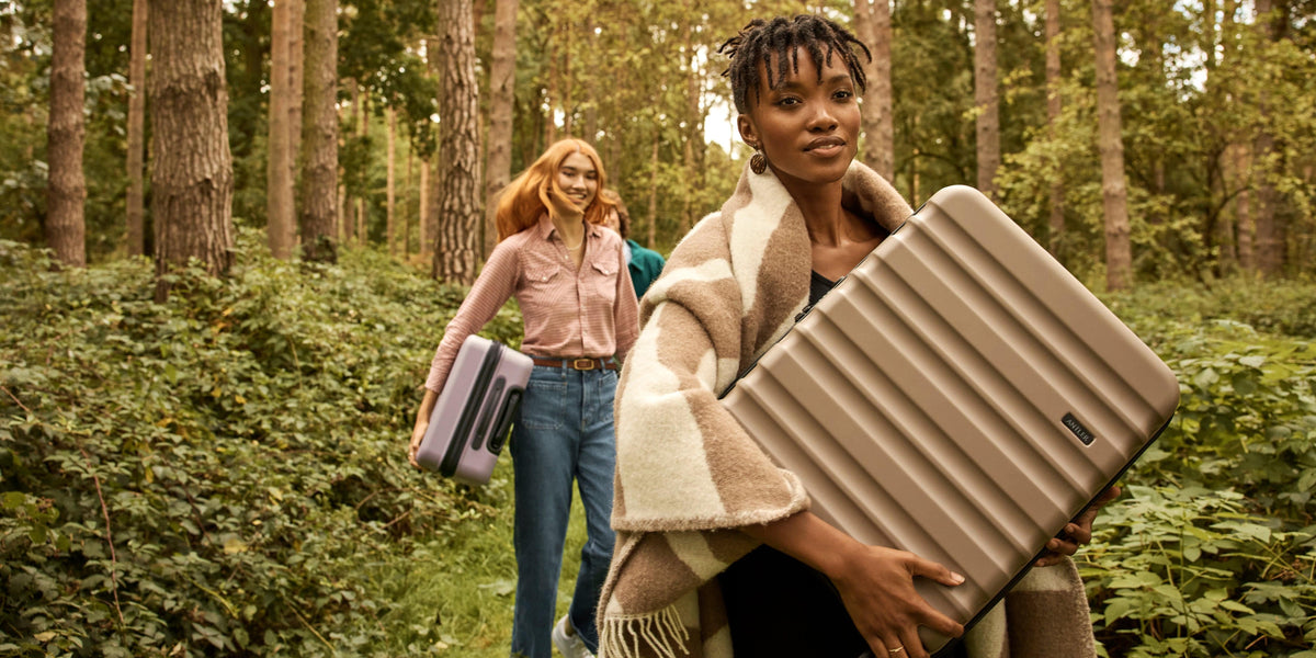 a woman carrying a suitcase in a forest