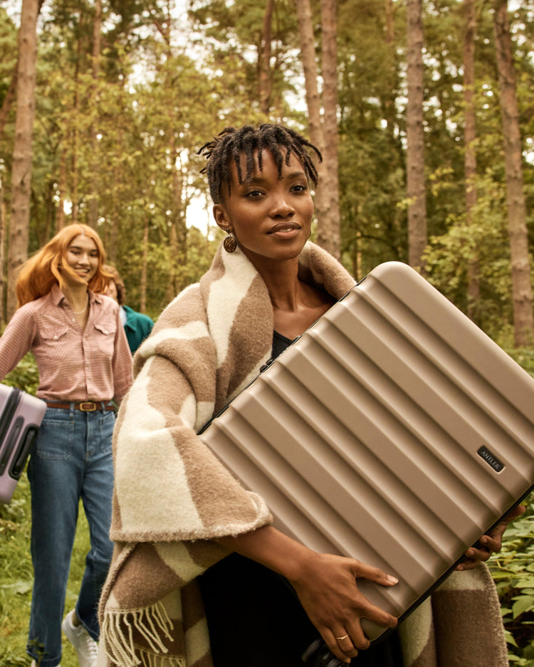 a woman holding a suitcase in a forest