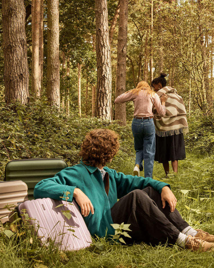 a group of people sitting in the grass with luggage