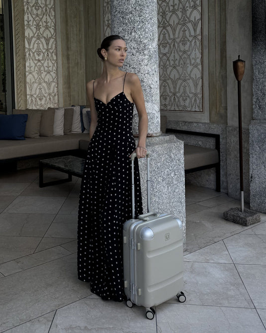 a woman in a black dress with a suitcase