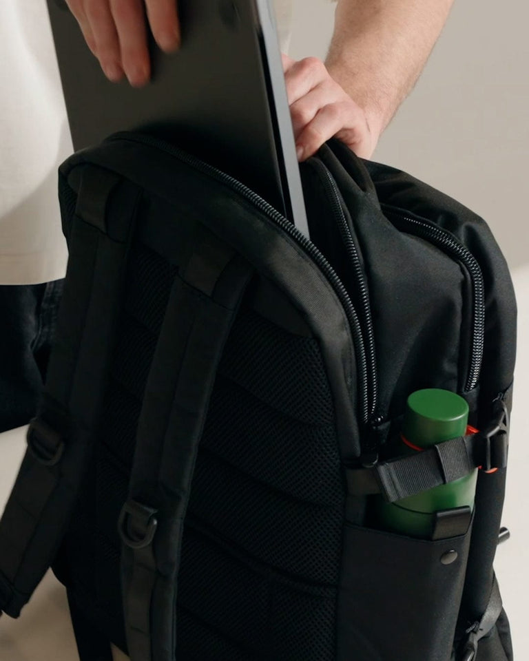 a person holding a laptop in a backpack