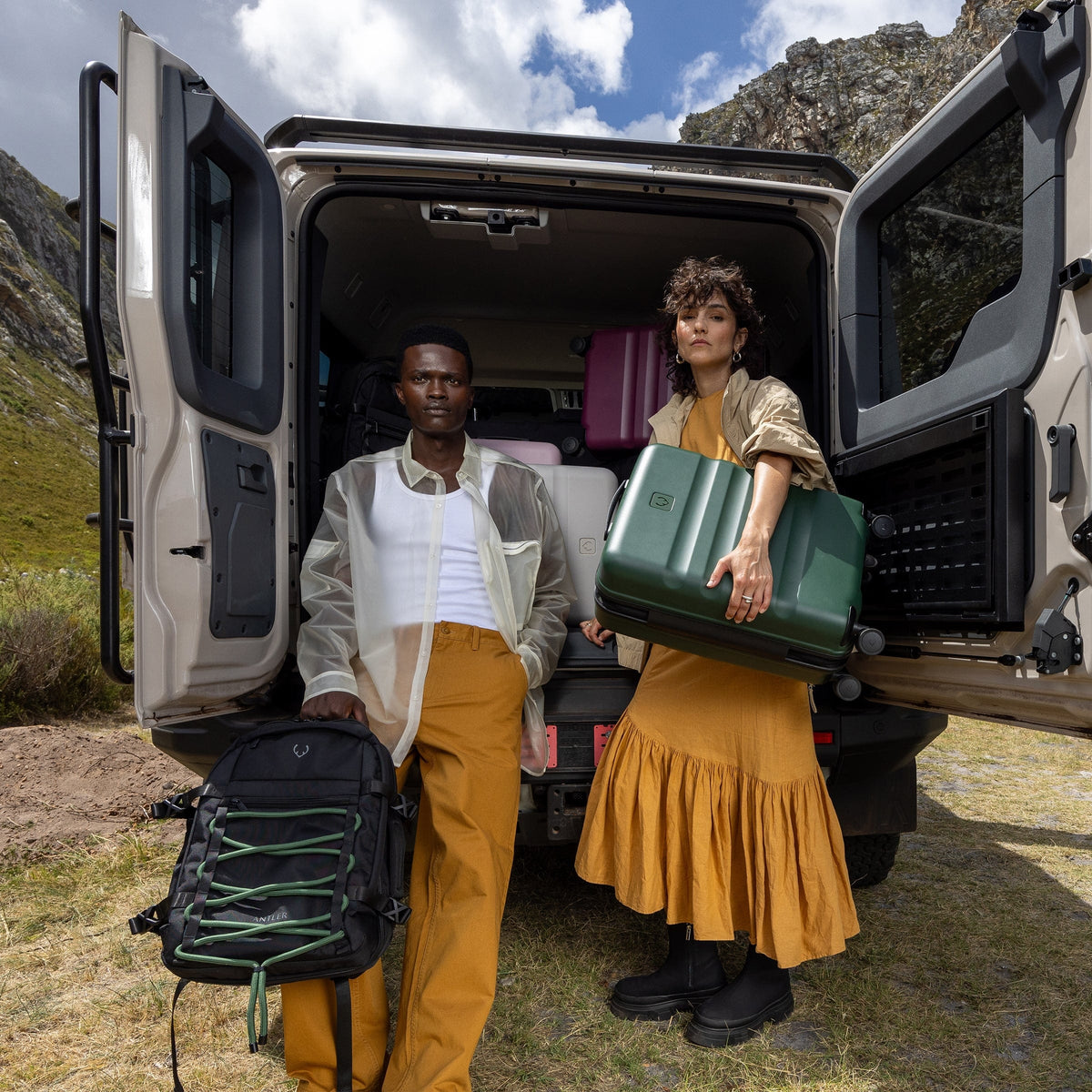 a man and woman standing in the back of a van with luggage