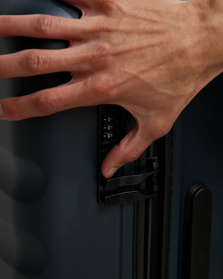 a hand holding a lock on a suitcase
