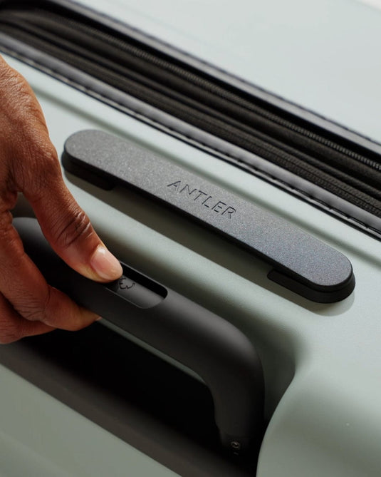 a hand holding a handle on a suitcase
