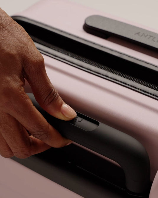 a hand holding a handle of a suitcase