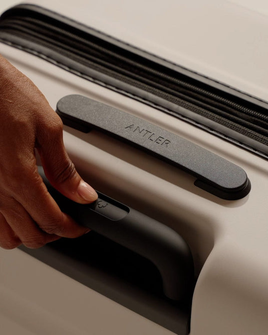 a hand holding a handle on a suitcase
