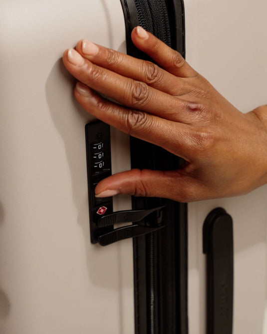 a hand holding a black handle on a suitcase