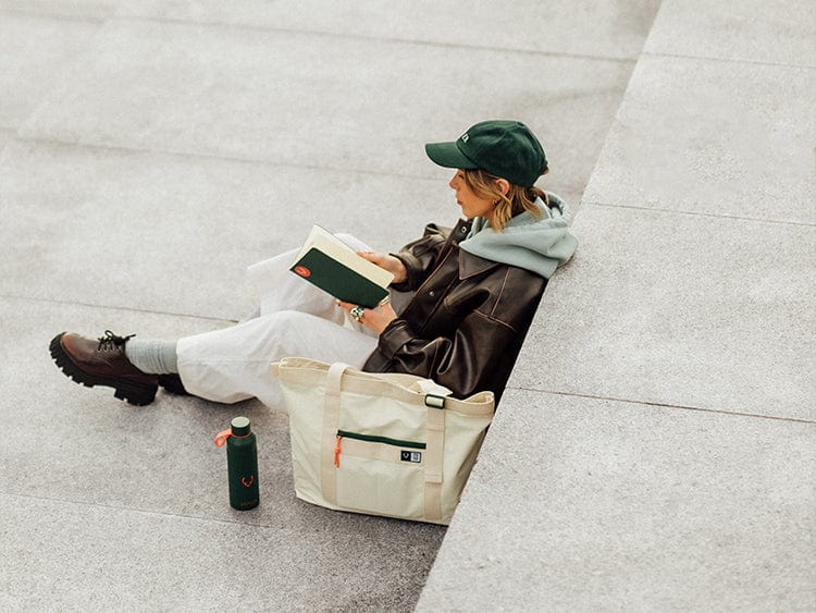 a woman sitting on a ledge reading a book
