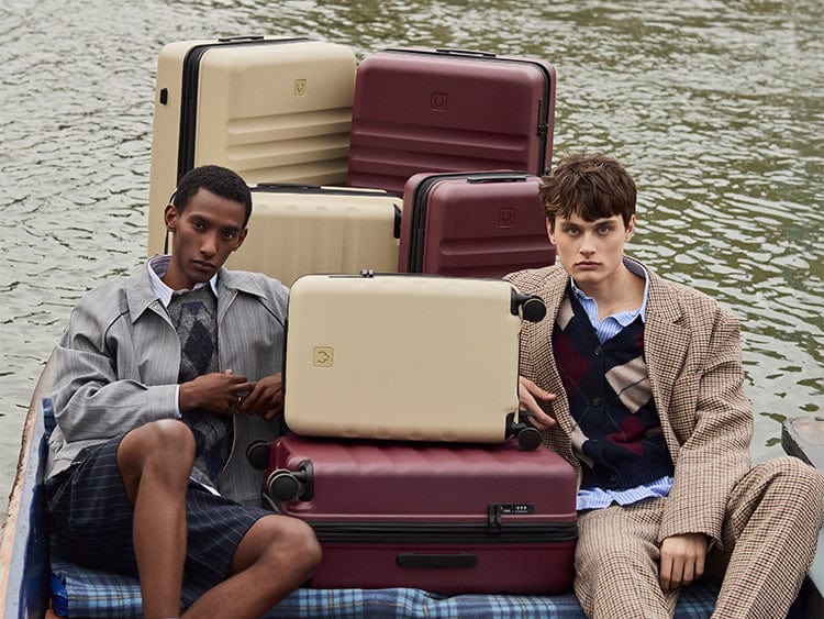 two men sitting on a blanket with luggage