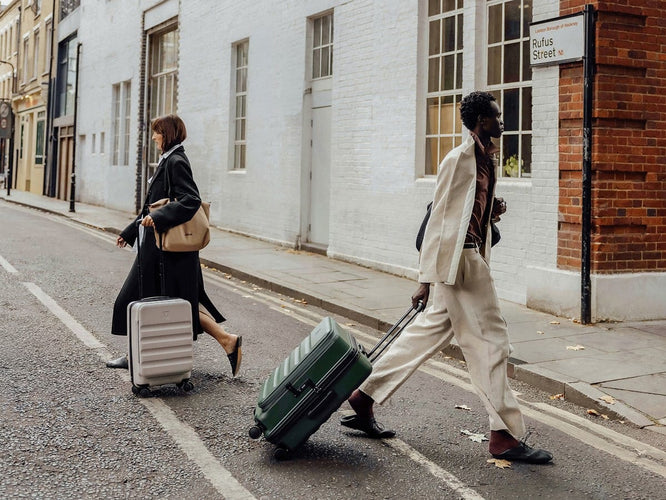 a man and woman walking on the street with luggage
