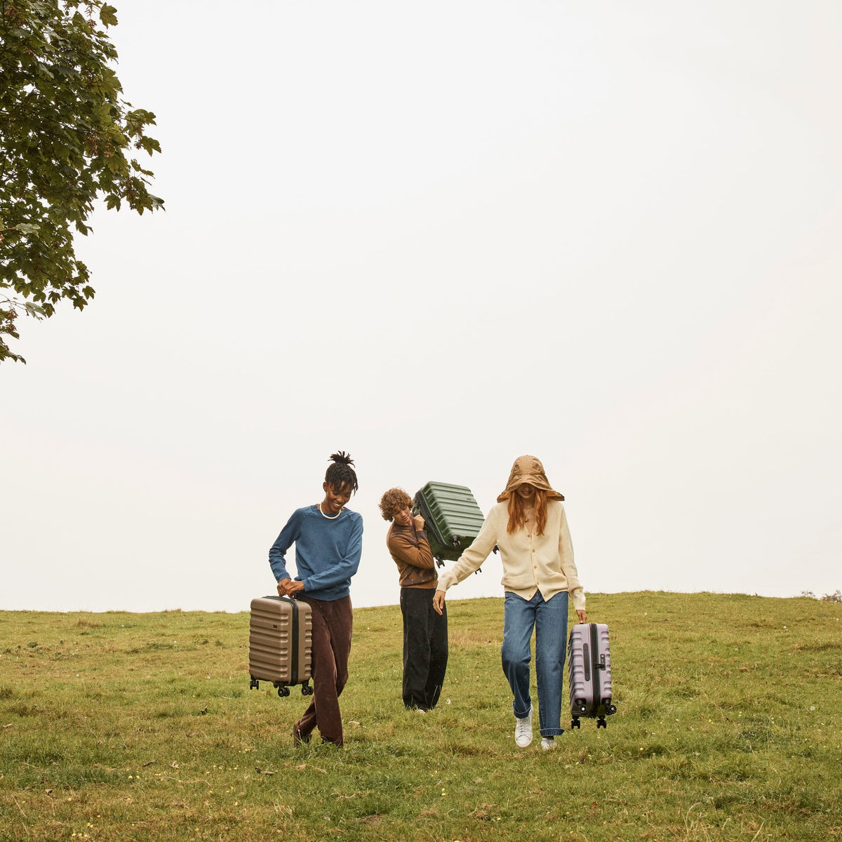 a group of people carrying luggage in a grassy field