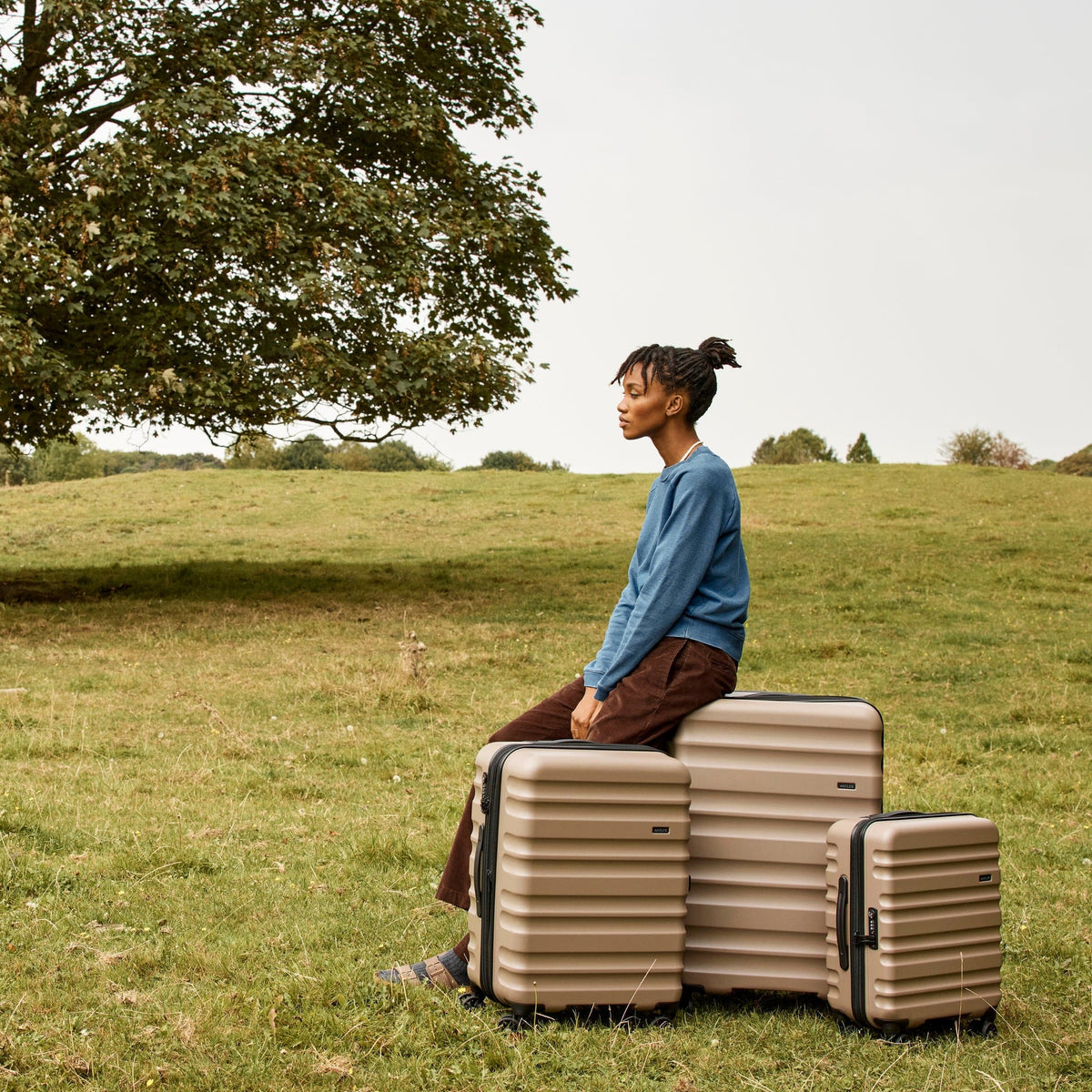 a woman sitting on luggage in a field
